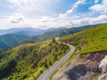 Scenic view of road by mountains against sky