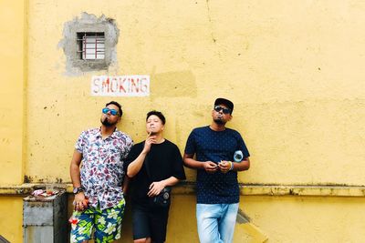 Full length of young woman standing against wall