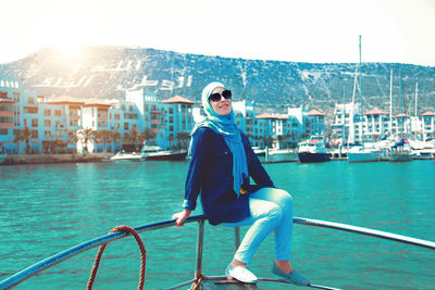 Portrait of smiling young woman sitting on boat sailing in sea