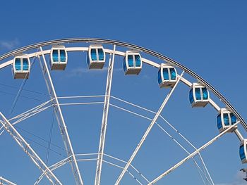 Low angle view of ferris wheel against clear blue sky