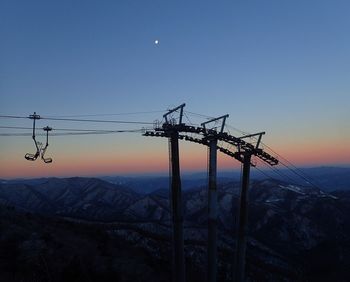 Low angle view of silhouette electricity pylon against sky at sunset