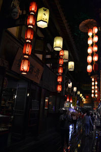 Illuminated lanterns hanging on street amidst buildings at night