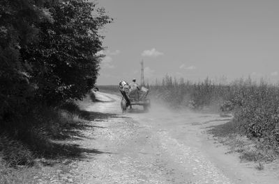 People riding bicycle on road against sky