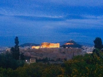 Trees on landscape against blue sky