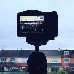 Close-up of camera against buildings in city