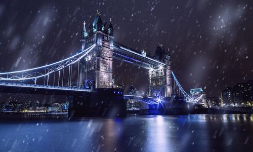 Illuminated suspension bridge in city against sky at night