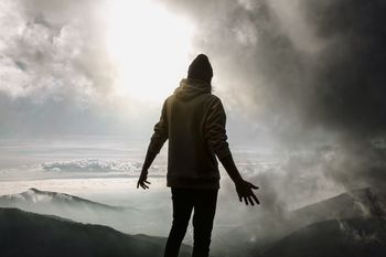 Rear view of man standing on mountain against sky