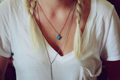 Midsection of woman with braided hair wearing hear pendant necklace