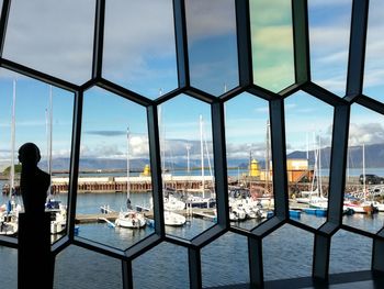 People on table by sea against sky seen through window