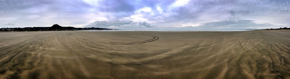 Scenic view of beach against cloudy sky