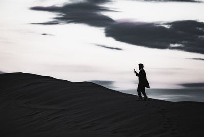 Rear view of man walking on beach against sky