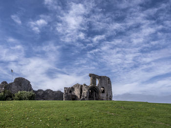 Old ruin building on field against cloudy sky