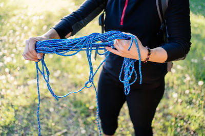 Midsection of woman holding rope on field