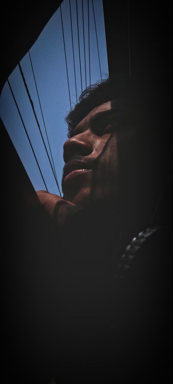 LOW ANGLE VIEW PORTRAIT OF MAN IN DARK ROOM