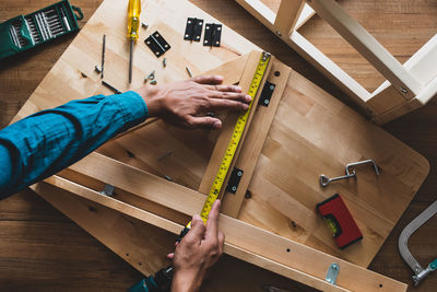 Cropped hands of carpenter measuring wood