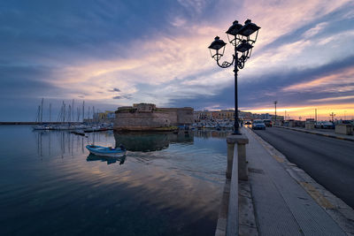Ship moored on river against sky at sunset