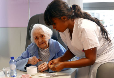 Nurse giving medicines to senior patient at hospital