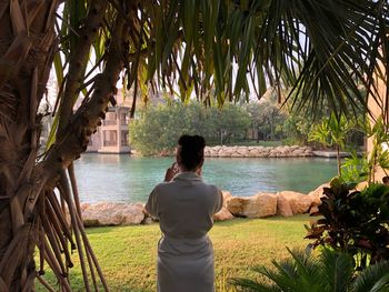 Rear view of woman standing against lake