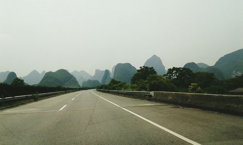 Road by mountains against clear sky