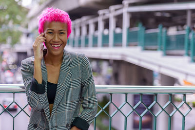 Portrait of smiling woman standing on mobile phone