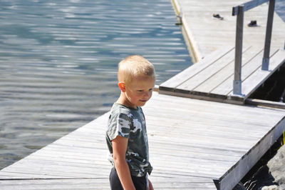 Boy standing on pier over lake