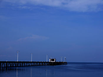 Pier over sea against blue sky