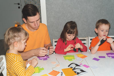 Father and siblings are preparing for the halloween holiday, making decorations 