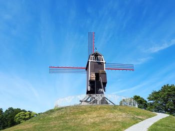 Low angle view of traditional windmill against blue sky in bruges