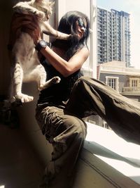 Woman holding cat while sitting at window