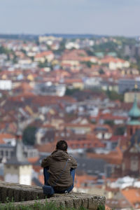 Rear view of man looking at city buildings against sky