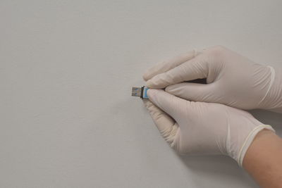 Close-up of man holding hands against white wall