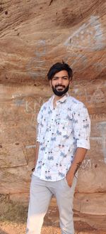 Portrait of young man standing against wall