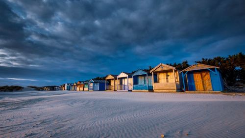 Houses on beach by buildings against sky