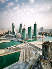 Aerial view of city at waterfront against cloudy sky