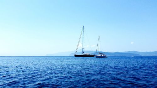 Sailboats in blue sea against sky