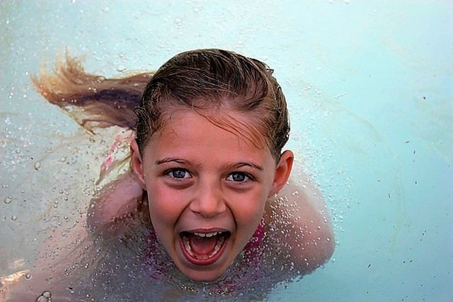 PORTRAIT OF SMILING GIRL SWIMMING IN WATER
