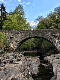 Arch bridge over river against sky