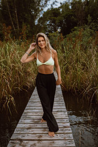 Portrait of young woman standing against lake