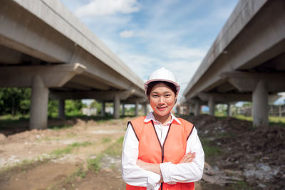 Portrait of young woman standing against building