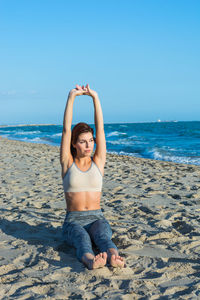 Young woman on beach against clear sky