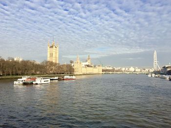 View of buildings by river against sky in city