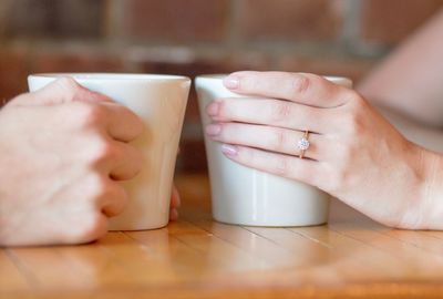 Midsection of woman with coffee cup on table