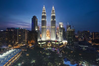 Illuminated petronas towers amidst buildings in city