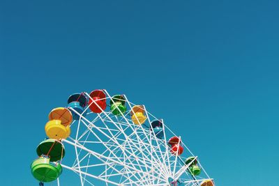 Low angle view of ferris wheel against clear blue sky