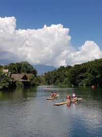 People on boat in lake against sky