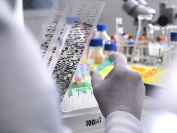 Scientist holding a dna gel revealing the genetic make up of the specimen in the vial