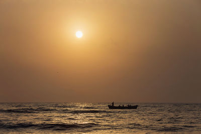 Silhouette boat sailing in sea against sky during sunset