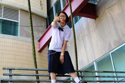 Portrait of girl wearing in-ear headphones while standing against building