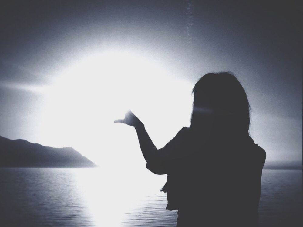 REAR VIEW OF SILHOUETTE WOMAN STANDING BY SEA AGAINST CLEAR SKY