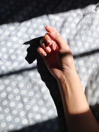 Cropped hand of woman on bed